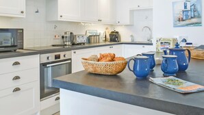 A modern kitchen with white cabinets, a microwave, toaster, kettle, and a basket of bread on the counter. - All that Salcombe has to offer from your perfect family base. (Salcombe)