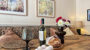 Una mesa de madera con una copa de vino, una botella de vino, huevos en un cuenco de madera, una hogaza de pan y un florero con flores.
