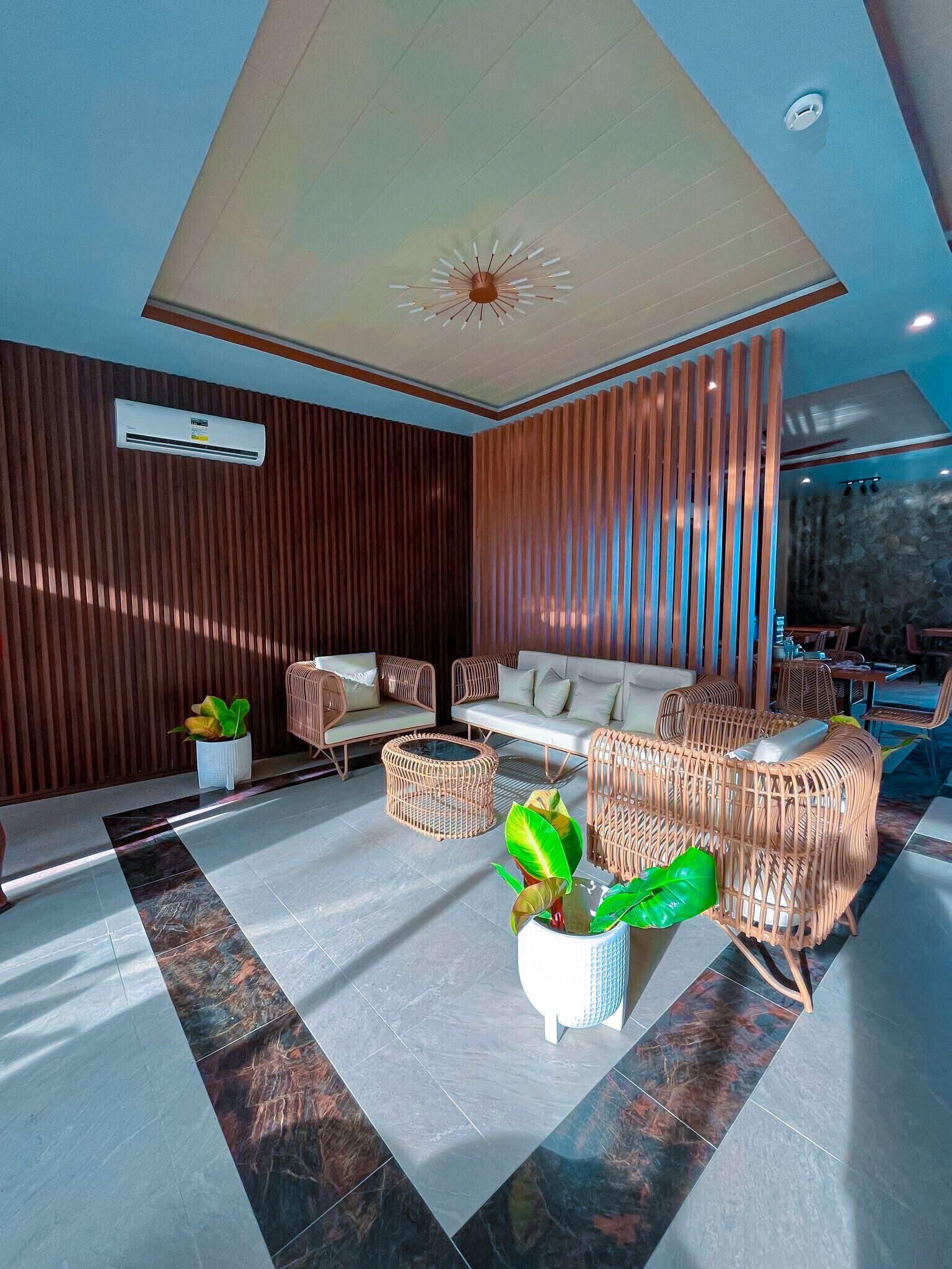 A modern lounge area with a sofa set, wicker chairs, and a ceiling fan.