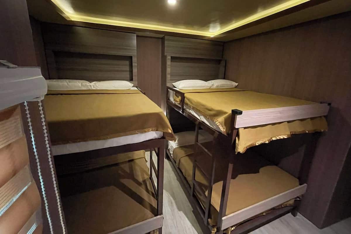Ein Zimmer mit zwei Etagenbetten, Holz-Kopfteilen und einer Deckenleuchte.