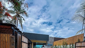 Un edificio moderno con fachada de piedra, valla de madera y un coche estacionado al frente.
