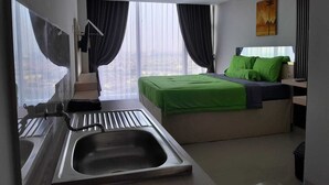 Una habitación de hotel moderna con una cama grande, un escritorio integrado, un lavamanos y vistas a la ciudad.