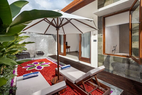 Un área de spa con terraza de madera, una sombrilla blanca y suelo estampado con flores.