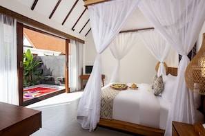 Une chambre à coucher avec un lit à baldaquin, une table de chevet, un petit bureau et une vue sur un jardin fleuri.