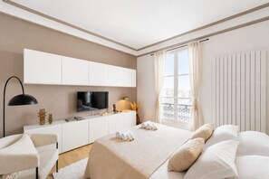 Une chambre d’hôtel avec un lit, un bureau, une télévision et une fenêtre avec des rideaux.