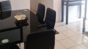 A dining area with a table and chairs, a television on a stand, and a door leading to another room.