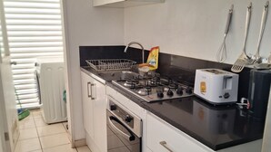A kitchen with white cabinets, a gas stove, a toaster, and a dish rack.
