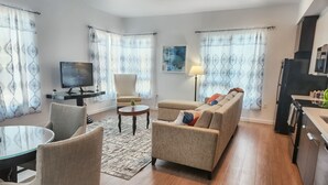 A modern living room with a sofa, armchairs, a coffee table, and a TV.