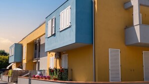 Una hilera de edificios modernos de dos pisos con balcones, cielo despejado y calle pavimentada.