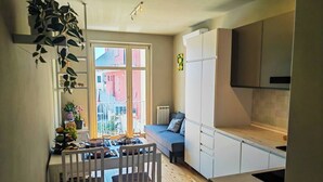 Cocina compacta con comedor, sofá y vistas al exterior.