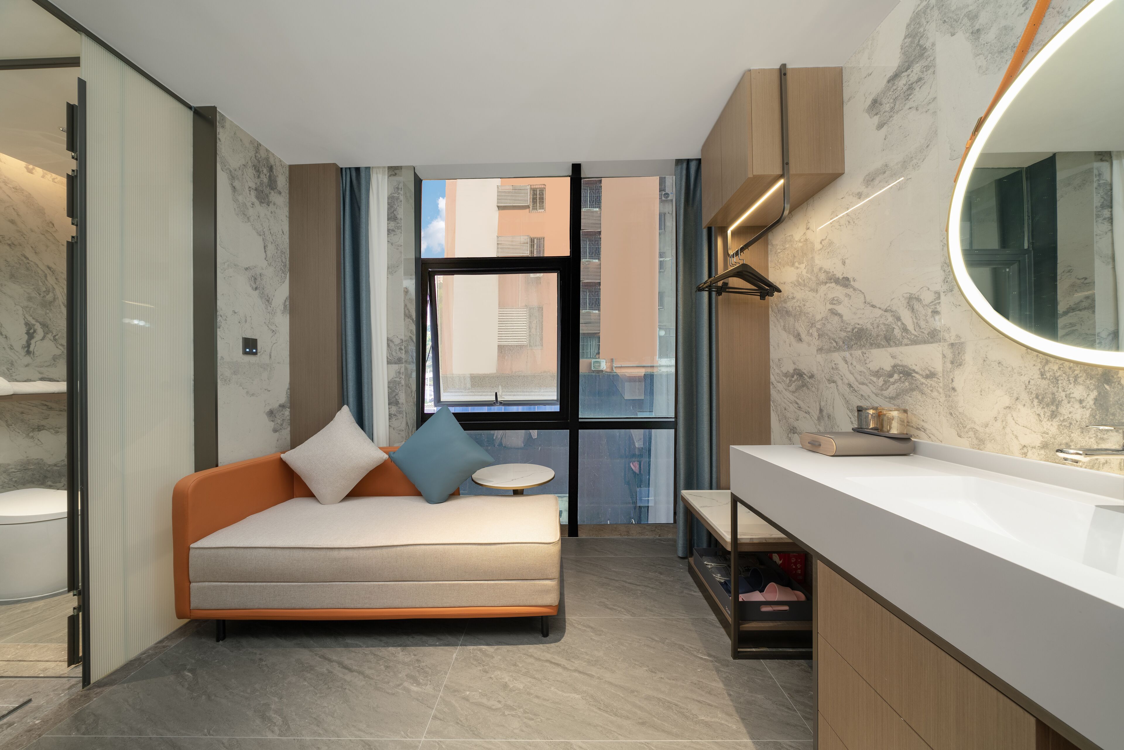 A modern bathroom with a marble wall, a built-in sink, and a large mirror.
