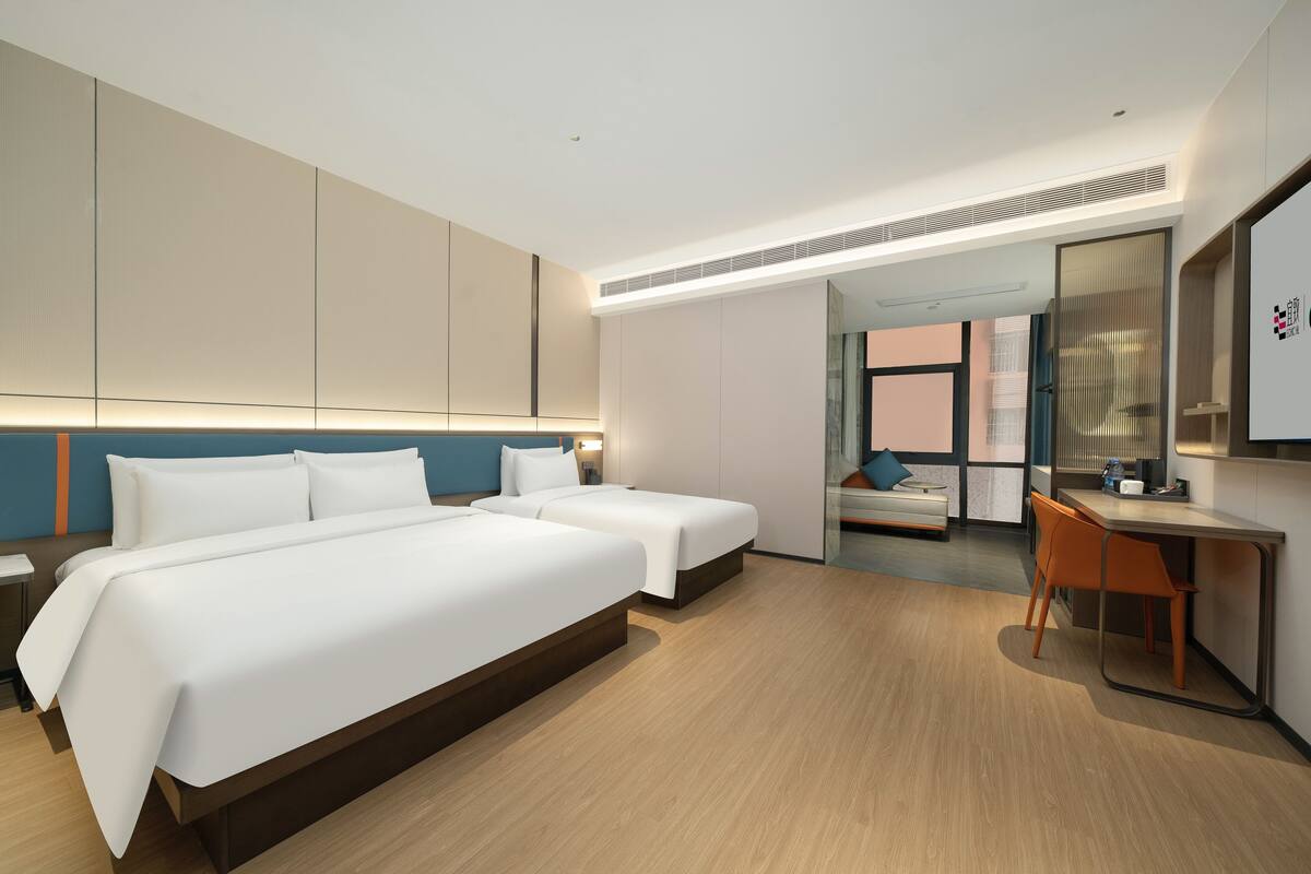A modern hotel room with two beds, a desk, and a chair.