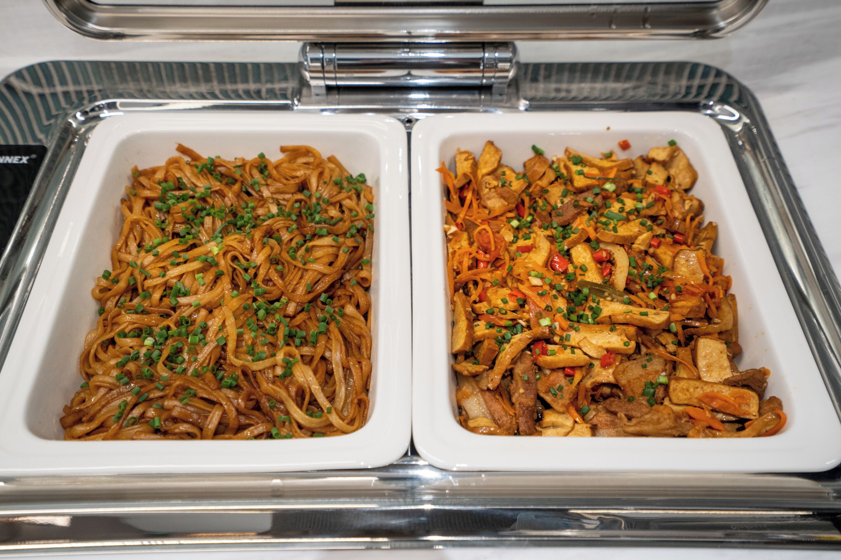Two white rectangular food containers with stir-fried noodles and mixed vegetables.