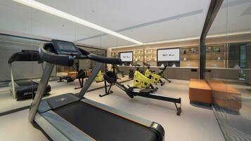 A modern gym with treadmills, stationary bikes, and a rowing machine.
