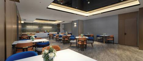 A modern dining area with multiple tables and chairs, a central floral arrangement, and a high ceiling with recessed lighting.