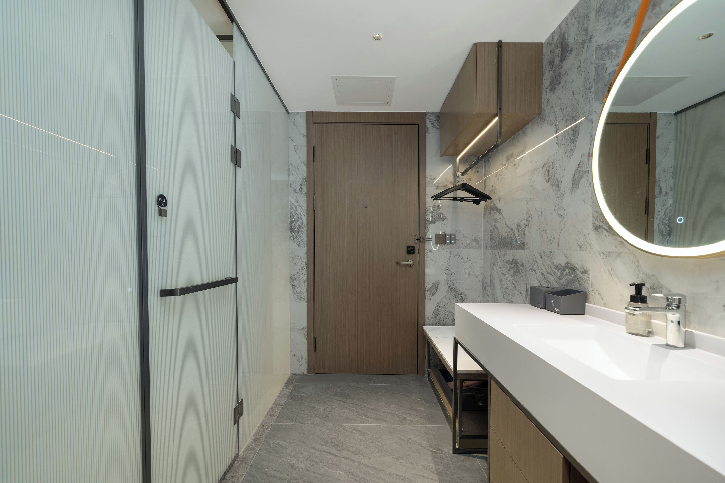 A modern bathroom with a marble backsplash, a large mirror, and a vanity with a sink and storage.