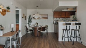 A modern kitchen with wooden cabinets, a central island with bar stools, and a dining area with a round table and chairs.
