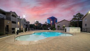 A swimming pool area with a sunset view, surrounded by apartment buildings.