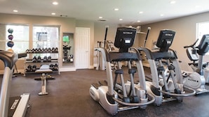 A gym with treadmills, elliptical machines, and free weights.