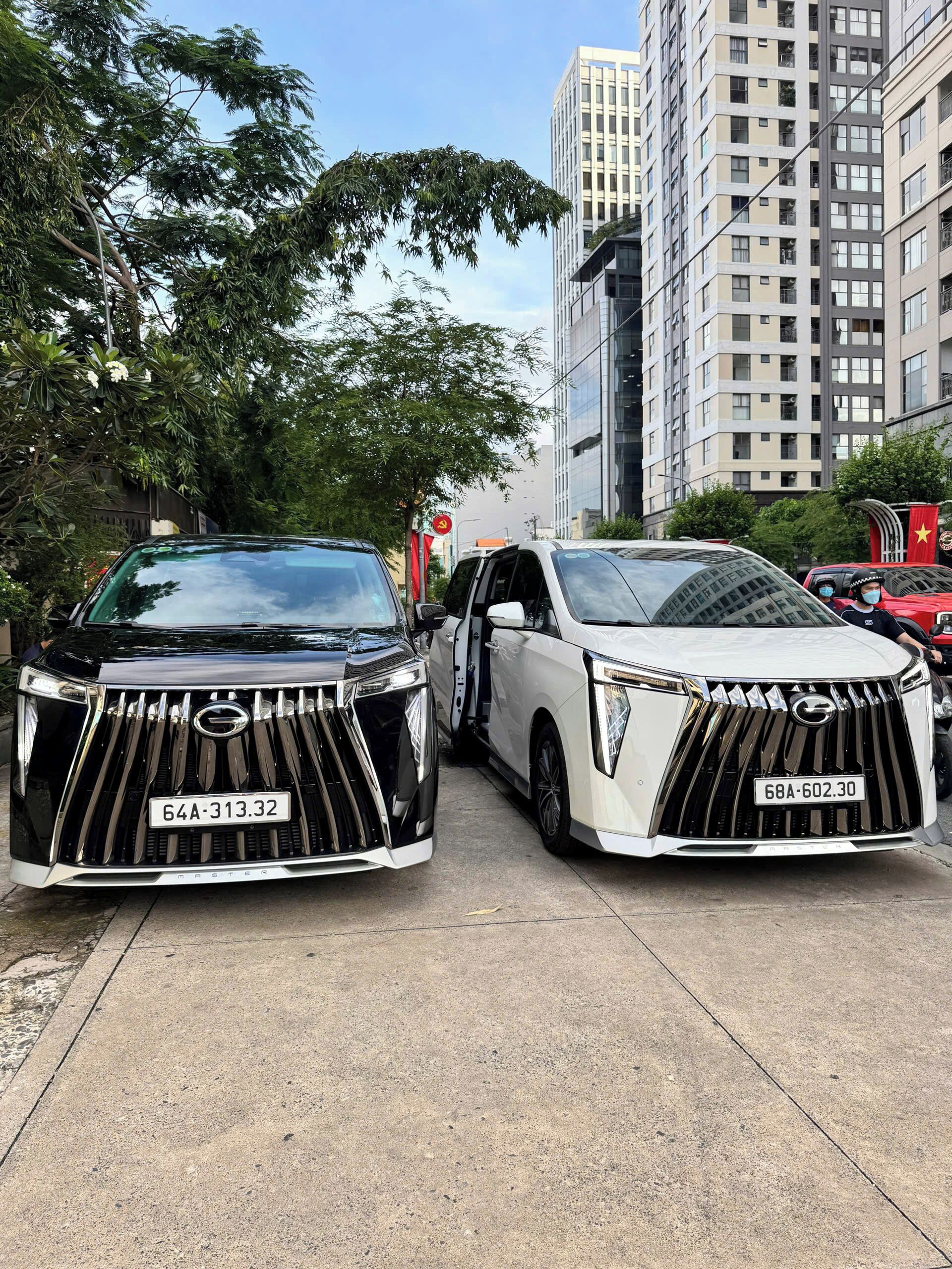 Deux voitures de luxe sont garées dans une rue de la ville, avec de grands immeubles en arrière-plan.