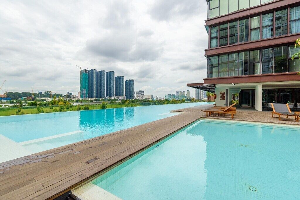 Une piscine avec une terrasse en bois, des chaises longues et une vue sur les gratte-ciel en arrière-plan.