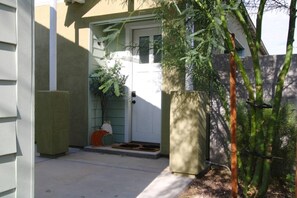 A residential entrance with a door, a small porch area, and a potted plant.