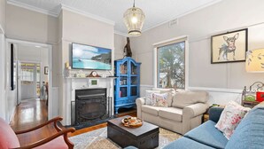 Un salon avec une cheminée, un meuble bleu, un canapé et un téléviseur.