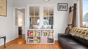 Un salon chaleureux avec une bibliothèque, un canapé en cuir et une fenêtre donnant sur un beau paysage.