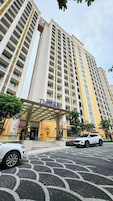 Un hotel moderno de altura con una entrada destacada y un cartel con el nombre.