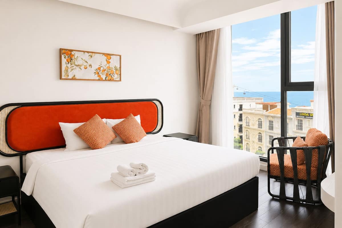 A hotel room with a large bed, a view of the city, and a chair by the window.