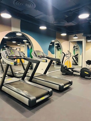 A gym with treadmills, elliptical machines, and a mirrored wall.