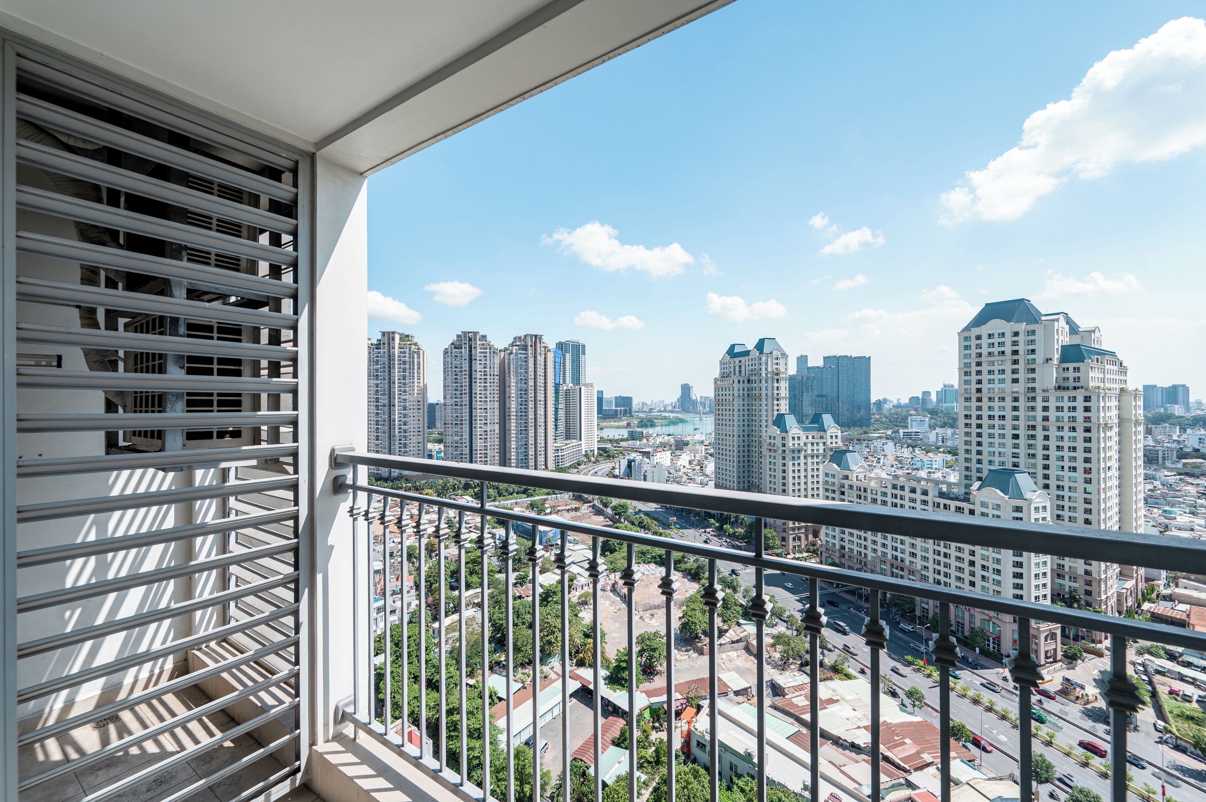 Un balcon offrant une vue sur le paysage urbain, avec de hauts immeubles et un ciel dégagé.