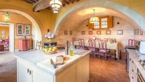 A spacious kitchen with an island, wooden ceiling beams, and a dining area with pink chairs.