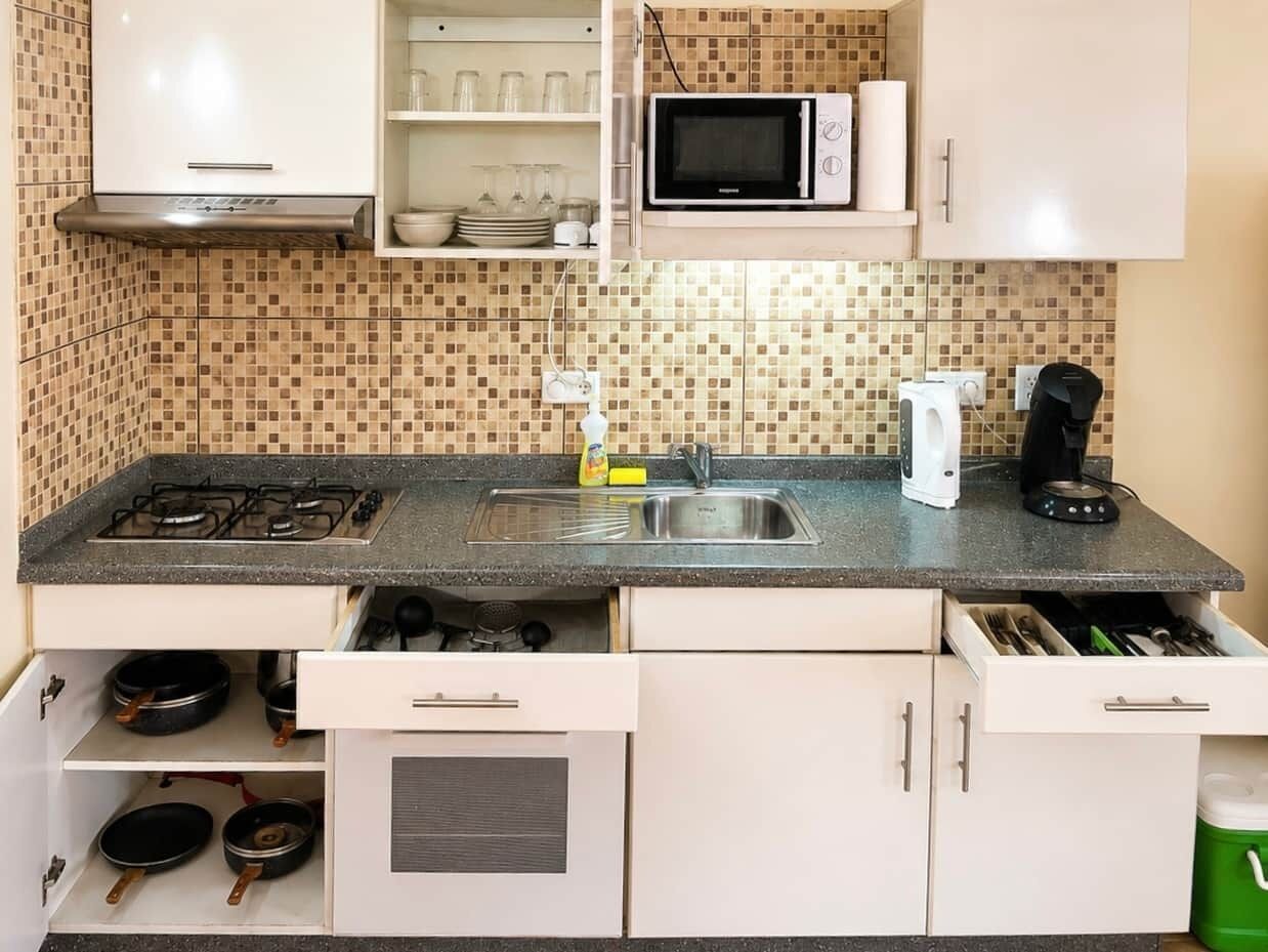 Een keuken met een gasfornuis, magnetron en diverse keukengerei.