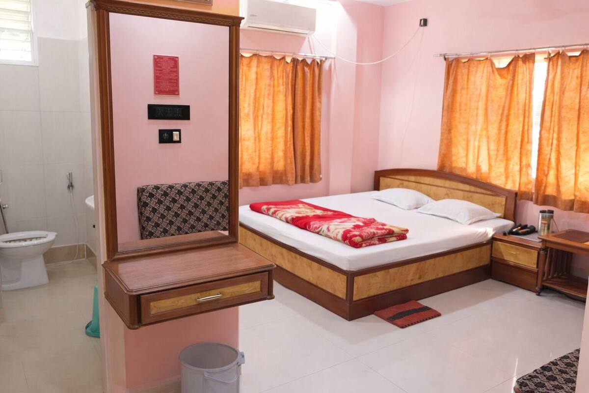 Une chambre d’hôtel comprenant un lit, une table de chevet, une commode, un miroir, des toilettes et une douche.