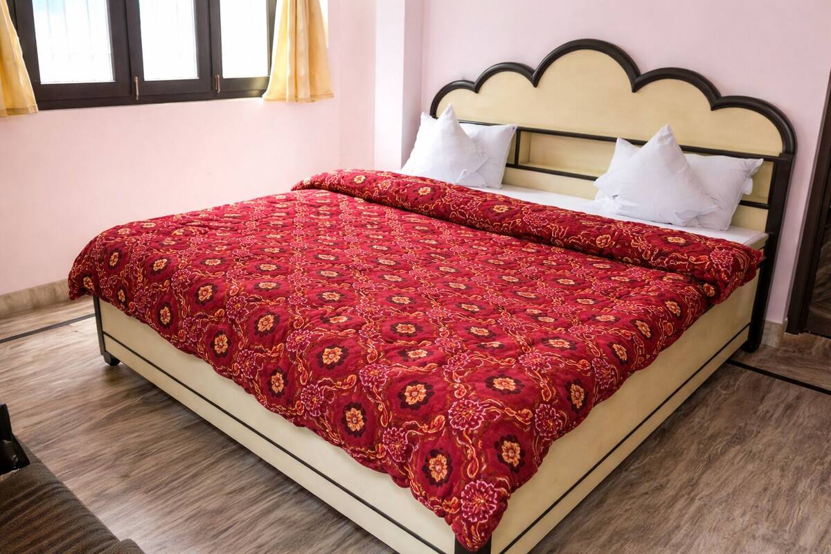 Un lit avec une couvre-lit à motifs floraux, une tête de lit à motifs festonnés et une fenêtre avec des rideaux.