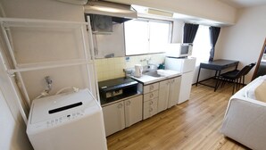 Una cocina compacta con lavadora, microondas y un pequeño comedor con mesa y sillas.