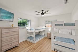Ein Schlafzimmer mit Etagenbetten, einem Schminktisch, einem Deckenventilator und einem Fenster mit Jalousien.