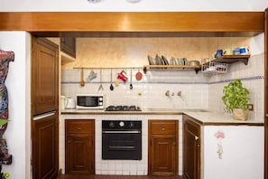 Une cuisine avec des meubles en bois, un four à micro-ondes, une cuisinière et des ustensiles suspendus.