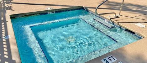 A swimming pool with a 3 FT depth marker, poolside lounge chairs, and a metal ladder.