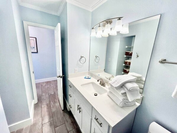 A bathroom with a white vanity, a large mirror, and a towel rack.