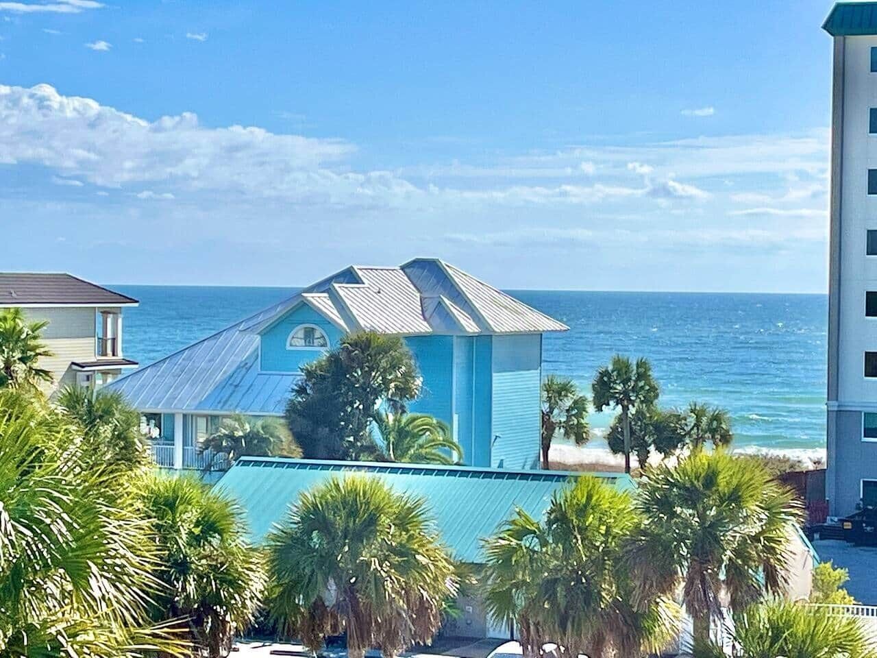 Un edificio frente al mar con fachada azul, un área de piscina y vistas al océano.
