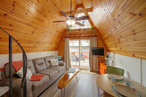 Ein gemütliches Interieur mit Holzbalkendecke, einer Couch, einem Esstisch und einem Fernseher.