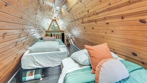 L'intérieur d'une cabine comprenant deux lits, un plafond en bois et une petite fenêtre.