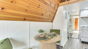 Un coin repas avec une table ronde, des chaises et une cuisine en arrière-plan.
