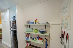 Eine Küche mit einem Kühlschrank, Regalen mit Geschirr und einer Wand mit einem Poster.