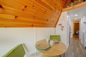 Ein Essbereich mit Holzboden, einem runden Tisch und grünen Stühlen.