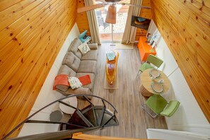 A compact living space with a sofa, a dining table, and a spiral staircase. - Cozy Cabin w/ Deck & Boat Launch Access in Lampe! (Lampe)