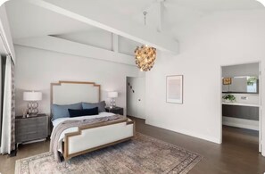 Un dormitorio moderno con una cama grande, mesitas de noche, un candelabro y un vestidor.
