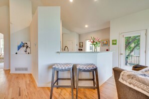 A modern kitchen with two stools, a white countertop, and a door leading to a balcony. - Pet-Friendly Longmont Home w/ McIntosh Lake Access (Longmont)